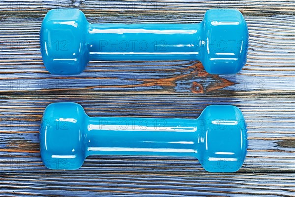 Blue fitness dumbbells on vintage wooden board