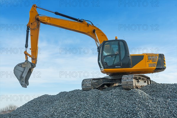 Excavator on big pile of gravel