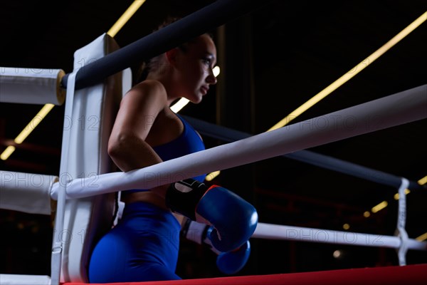Powerful charged girl stands in the corner of the ring and is ready to explode in the next round. The concept of wrestling and boxing. Mixed media