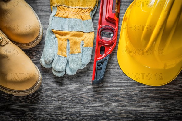 Construction level protective gloves hard hat lace boots on wooden board