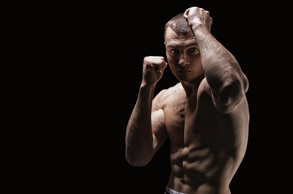 Professional boxer posing in the studio. He stands in front of the camera and elbows. The concept of sport