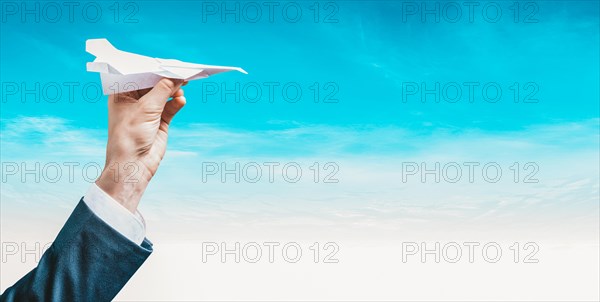 Image of a hand holding a paper airplane. Tourism concept.