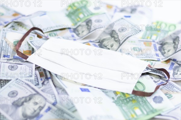 Medical mask rests on one hundred dollar bills. The concept of an epidemic