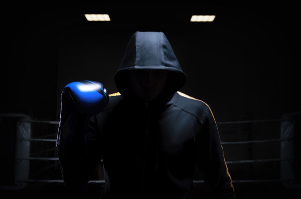 World champion in Thai boxing stands in the background of the ring with a raised blue glove. The concept of sport