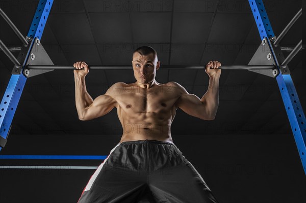 The athlete pulls himself on the horizontal bar behind his head. The concept of sport and healthy lifestyle.