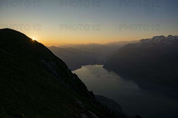Mountain ridge with mountaineers and Swiss mountains and Lake Thun in the background at sunrise