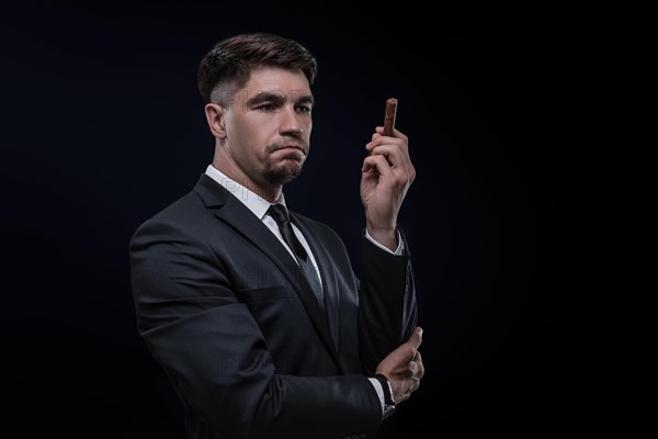 Portrait of a stylish man in a suit with a cigar. Business concept.