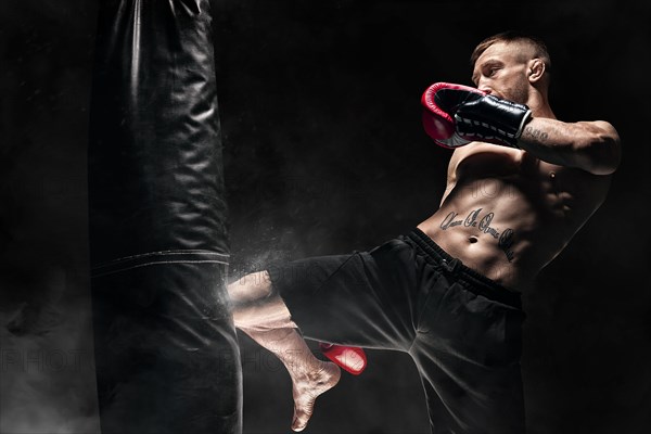 Kickboxer hits the bag with his knee. Training a professional athlete. The concept of mma