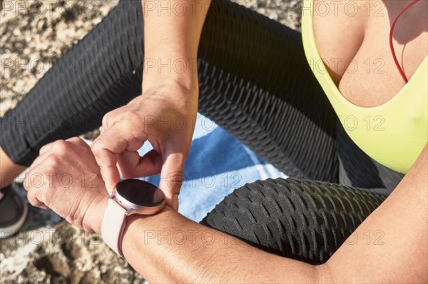 Close-up of a person checking a smartwatch while wearing sportswear during an outdoor workout