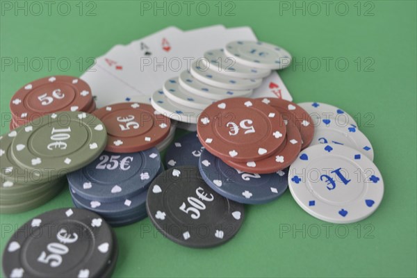 Stacks of poker chips and a fan of playing cards on a green felt gaming table