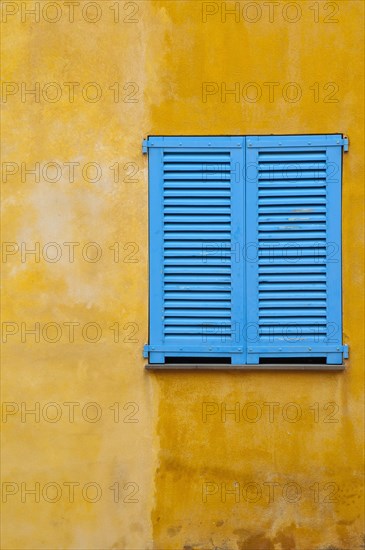 Blue shutter on yellow plaster wall