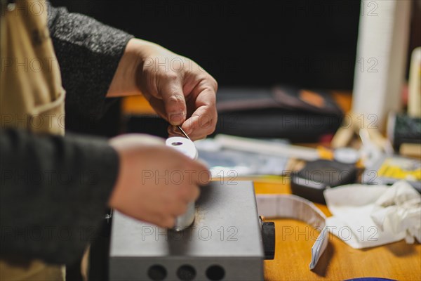 Unrecognizable luthier lute maker artisan both hands performing bend controller purfling strips process in iron tool for a new raw back and front plates of classic handmade violin in his workshop in C...