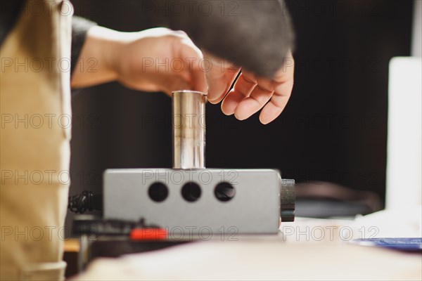 Unrecognizable luthier lute maker artisan both hands performing bend controller purfling strips process in iron tool for a new raw back and front plates of classic handmade violin in his workshop in C...