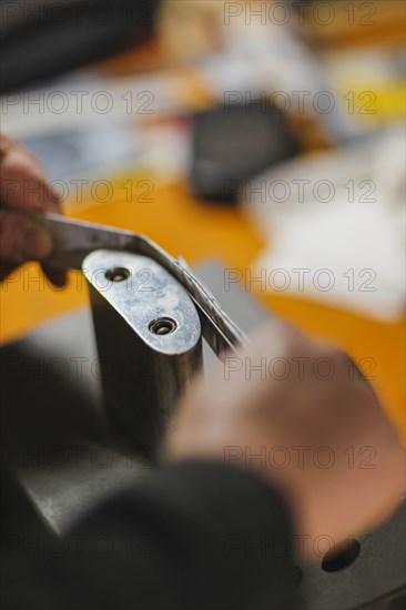 Unrecognizable luthier lute maker artisan hands in his workshop performing bend controller purfling strips process in iron tool for a new raw back and front plates of classic handmade violin in Cremon...