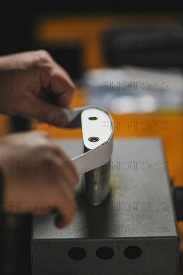 Unrecognizable luthier lute maker artisan both hands performing bend controller purfling strips process in iron tool for a new raw back and front plates of classic handmade violin in his workshop in C...