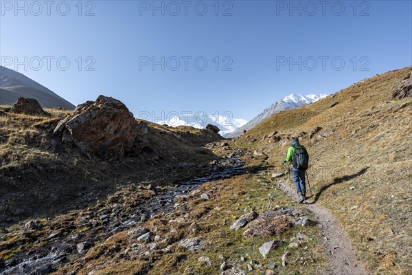 Hikers in the Achik-Tash valley, snow-covered mountain peak Pik Lenin in the background, Trans Alay