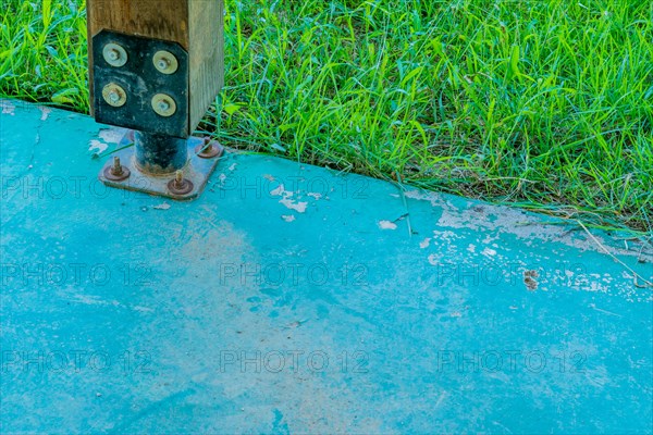 Square wooden support column attached to concrete base using metal anchor plate