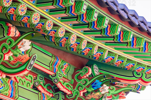 Eve of a Buddhist temple building with vibrant green, red, blue, and white colors representing the