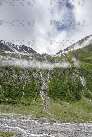 Mountain streams flow over steep mountain slopes into the Schlegeisgrund valley, cloudy rocky