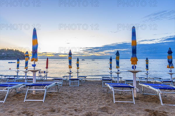Sun loungers and parasols on Straccolignino beach at sunrise, near Capoliveri, Elba, Tuscan
