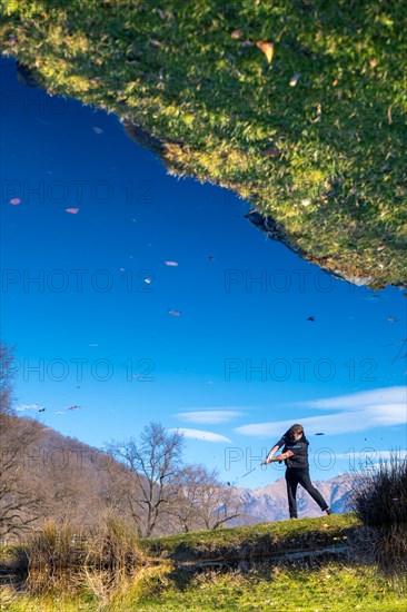 Male Golfer Reflected in a Water Pond and Hitting the Golf Ball on Fairway on Golf Course with