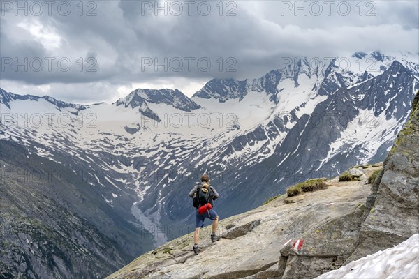 Mountaineer on hiking trail, view of glaciated rocky mountain peaks Hoher Weisszint and Hochfeiler