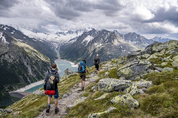 Mountaineer on hiking trail, view of Schlegeisspeicher, glaciated rocky mountain peaks Hoher