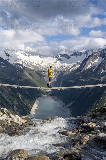 Mountaineers on a suspension bridge over a mountain stream Alelebach, picturesque mountain