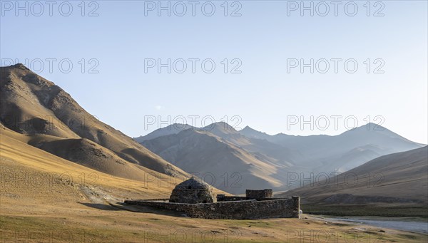 Historic caravanserai Tash Rabat from the 15th century, in the evening light with golden hills,