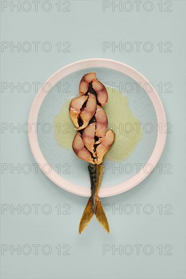 Sliced mackerel on a plate revealing its pinkish inner flesh against the darker outer skin. The