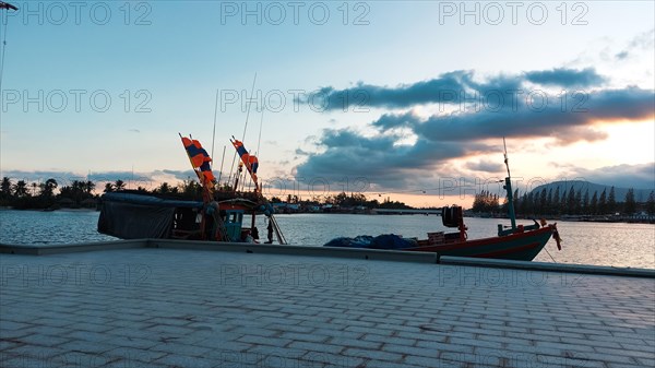 Sunset view over the river with silhouette of moored traditional khmer fishing boat in Kampot