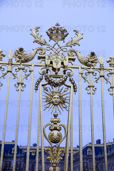 Emblem of the Sun King with Apollo's head, sunbeams and sceptre with French lily on the royal