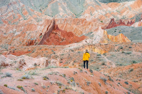 Hiker in front of eroded mountain landscape, sandstone cliffs, canyon with red and orange rock