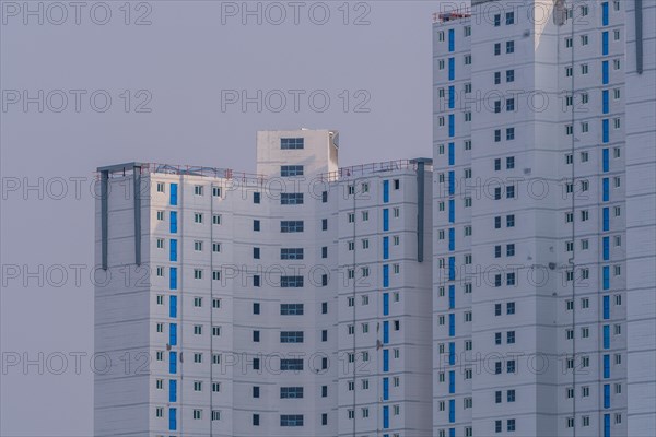 New highrise apartments with unfinished white concrete exterior walls and blue coverings on widow