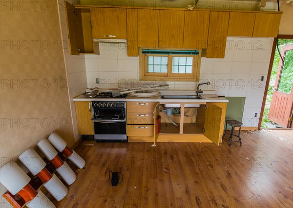 Kitchen area of abandoned house with dirt and electrical fixtures debris on counter top and leaning
