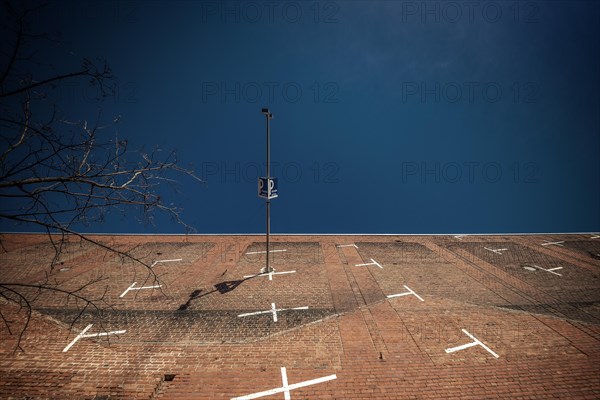 A lamppost and a car park sign in front of a brick wall with white lines, Cologne Deutz, North