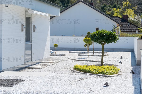 Modern garden with geometric shapes and spotlights next to a white house, residential design in