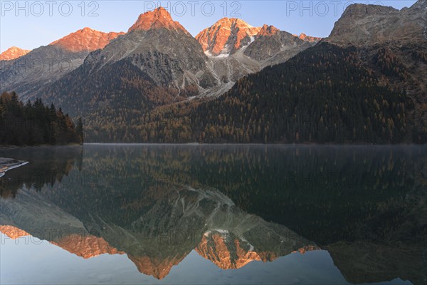 Mountains reflected in a mountain lake at sunrise, autumn, Lake Antholz, Rieserferner Group, South