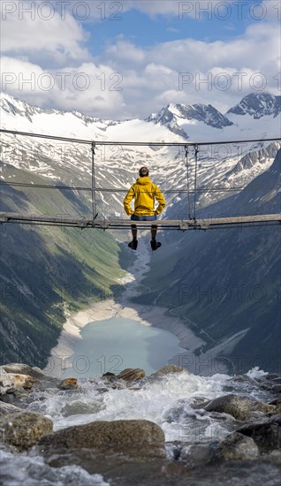 Mountaineer sitting on a suspension bridge over a mountain stream Alelebach, picturesque mountain