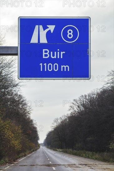 A traffic sign with a directional arrow points to the Buir motorway exit under a blue sky,