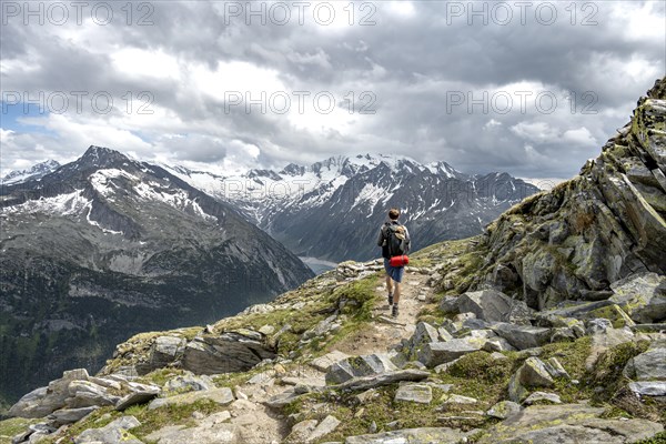 Mountaineer on hiking trail with snow, Berliner Hoehenweg, mountain landscape with glaciated peaks