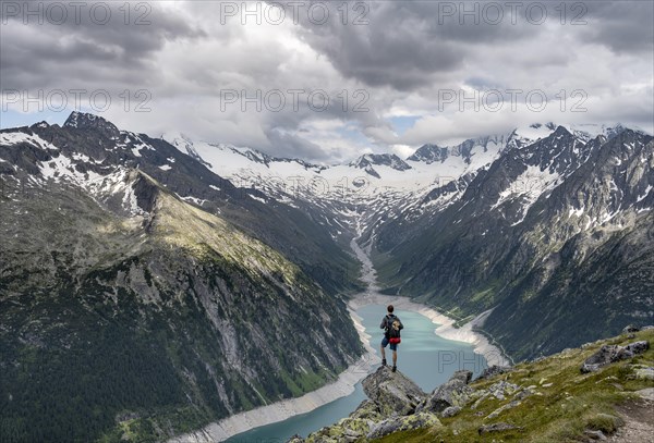 Mountaineer on a rock in front of a mountain panorama, view of Schlegeisspeicher, glaciated rocky