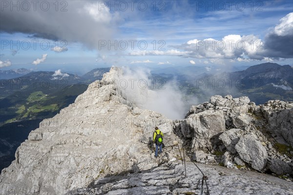 Climber on a via ferrata secured with steel rope, narrow rocky ridge, Watzmann crossing to Watzmann