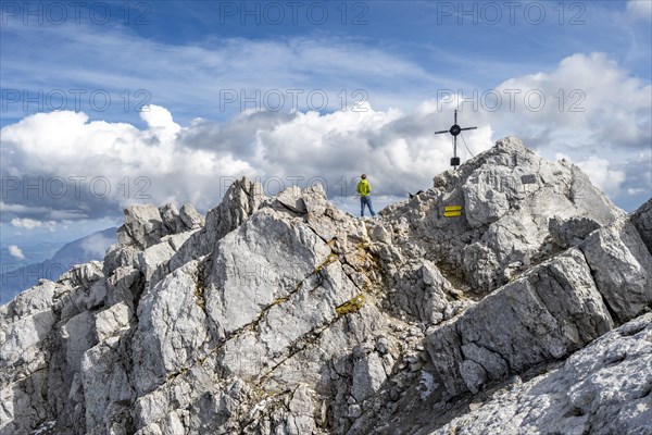 Mountaineer on the rocky summit of the Watzmann Mittelspitze with summit cross, Watzmann crossing,