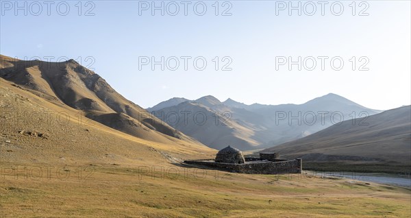 Historic caravanserai Tash Rabat from the 15th century, in the evening light with golden hills,
