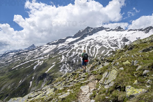 Mountaineer on rocky hiking trail, Berliner Hoehenweg, mountain landscape with snow-covered peak