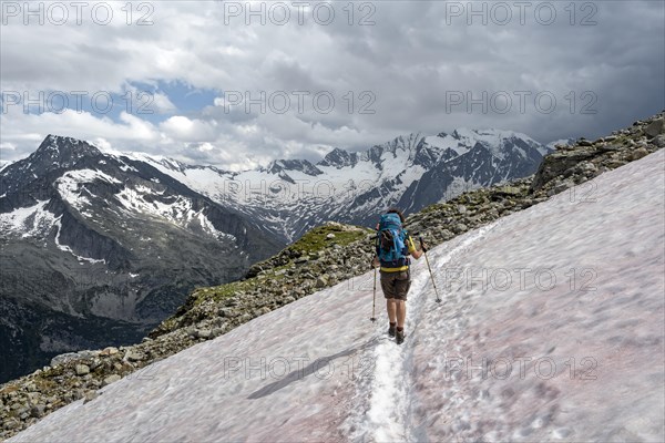 Mountaineer on hiking trail with snow, Berliner Hoehenweg, mountain landscape with glaciated peaks