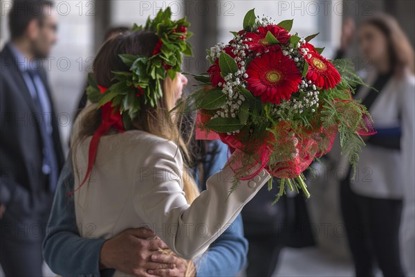 Joyful graduate of the University of Genoa with traditional laurel wreath and red ribbon and