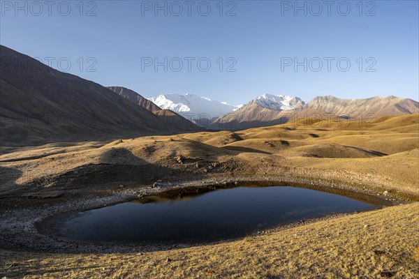 White glaciated and snow-covered mountain peak Pik Lenin at sunrise, mountain landscape with golden