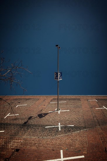 Lighting column and car park sign cast a shadow on a large brick wall, Cologne Deutz, North